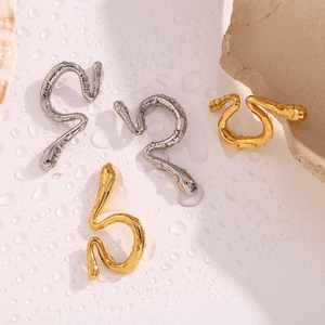 Detailed view of liquid-style irregular ear cuffs in gold and silver on a wet surface
