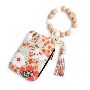Detail of floral printed card holder wallet with silicone bead wristlet and tassel charm