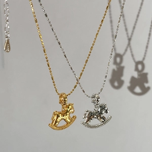 Detail of 18k gold and silver rocking horse pendants on bead chains with shadow effect