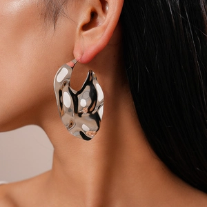 Gros plan sur les boucles d'oreilles argentées style métal liquide et forme irrégulière