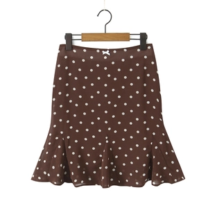 Detail of brown polka dot fishtail skirt with a white bow on wooden hanger