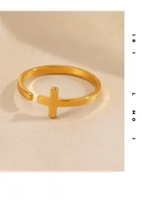 Close-up of golden stainless steel cross open ring on soft beige fabric background