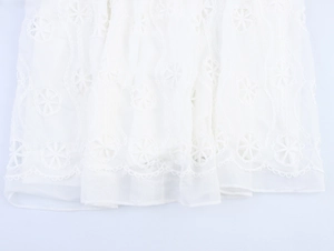 Détail de broderie florale blanche et ourlet en dentelle festonnée sur robe française