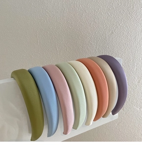 Row of candy-colored wide headbands in matte finish displayed on a white stand