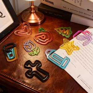 Close-up of colorful heart and star shaped resin paperclips on a vintage leather desk