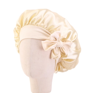 Dettaglio della cuffia da notte in raso champagne per bambini con grande fiocco decorativo