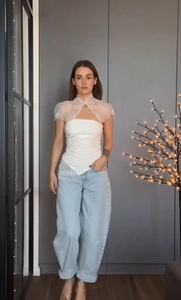 Détail d'un top bustier blanc avec châle en dentelle et jean large bleu clair