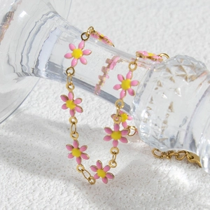 Elegant gold-tone stainless steel bracelet featuring delicate pink daisy charms