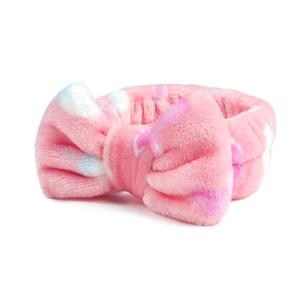Detailopname van de roze koraalfleece haarband met zachte pluche textuur en stippen