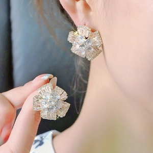 Elegant silver flower stud earrings with sparkling cubic zirconia on a model's ear