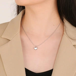 Detail of silver heart pendant with snake chain worn on model for elegant styling