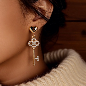 Macro shot of 18k gold plated heart lock and key drop earrings with sparkling crystals