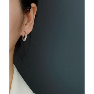 Close-up of elegant silver hoop earrings with small pearls worn by a model in profile