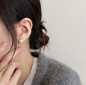 Close-up of elegant pearl earrings and necklace set on model with a soft aesthetic