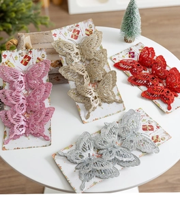 Glittery Christmas butterfly ornaments in red, pink, gold, and silver on white table