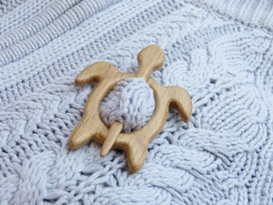 Close-up of a wooden turtle brooch pin fastening a light grey knitted fabric