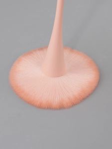 Close-up of soft peach makeup brush bristles with a smooth skin-like handle texture