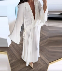 Close-up of deep V-neck with ruffled details and flared sleeves on white long dress