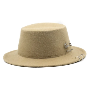 Detail of camel boater hat featuring punk-style silver metal rings and safety pin accents