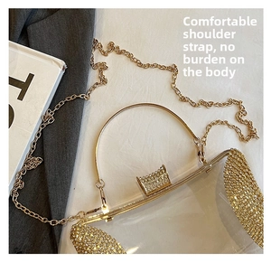 Close-up of transparent acrylic clutch with gold metal chain and sparkling rhinestones
