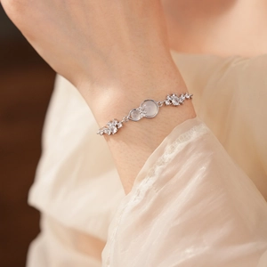 Detailed view of silver bow bracelet with zircons and moonstones on a woman's wrist
