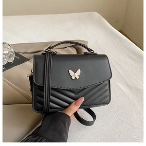 Close-up of black crossbody bag with V-quilted texture and butterfly metal clasp