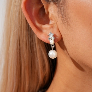 Détail de boucles d'oreilles pendantes avec cristaux brillants et perle nacrée blanche