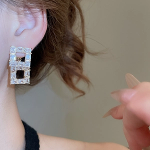 Macro view of square hollow earrings with 18K gold plating and cubic zirconia on a model