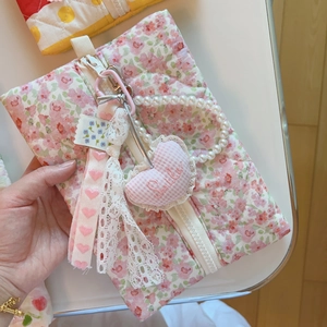 Détail de la pochette fleurie matelassée avec ruban de dentelle et chaîne de perles