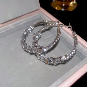 Close-up of silver geometric hoop earrings with sparkling crystals in a pink jewelry box