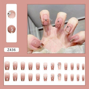 Detail of pink gradient press-on nails featuring pearls, rhinestones, and gold wire