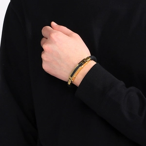 Close-up of men's braided leather bracelet featuring a gold plate with carbon fiber inlay