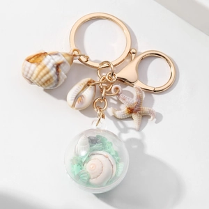 Zeester sleutelhanger met paillettenbal en schelpen op een witte achtergrond