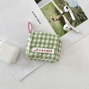 Detalle de funda de tela a cuadros verdes para auriculares con cordón rosa