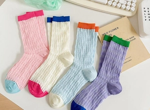 Detail of four colorful breathable mesh mid-calf socks for women in various pastel colors