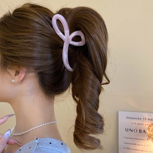 Detail of pink marble acetate bow hair claw clip showing glossy texture on hair