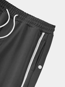 Detail of grey joggers featuring elastic waist, white drawstring, and button pocket