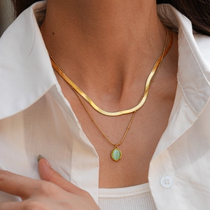 Gros plan d'un collier doré à double rangée avec pendentif ovale en opale verte chic