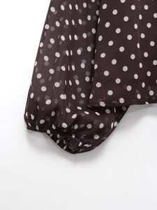 Detail of coffee brown polka dot chiffon fabric showing elastic lantern sleeve cuffs