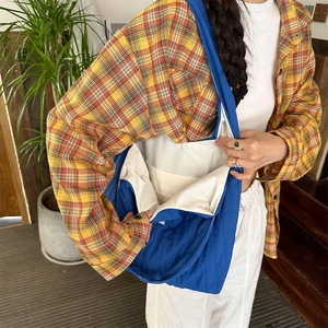 Detail of blue quilted shoulder bag showing spacious interior and soft fabric texture