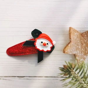 Detail of Christmas hair clip with red sequin base, green bow and Santa Claus icon