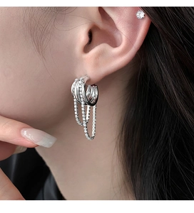 Close-up of silver multilayer hoop earrings with crystal tassels worn by a model