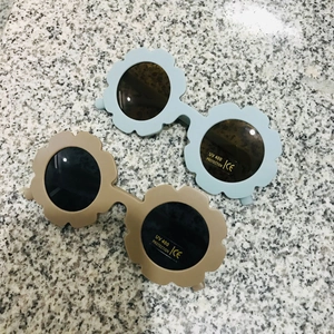 Detail view of flower-shaped kids sunglasses in light blue and khaki with UV400 protection
