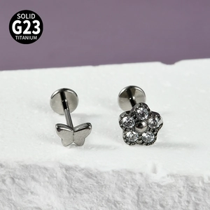 Détail macro de clous en titane G23 avec motifs de papillon et fleurs en zircone