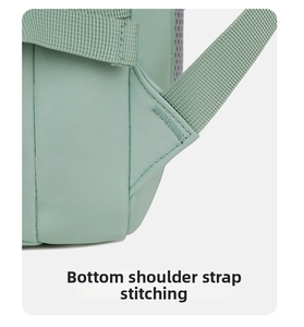 Close-up detail of mint green travel backpack shoulder strap bartack stitching reinforcement.