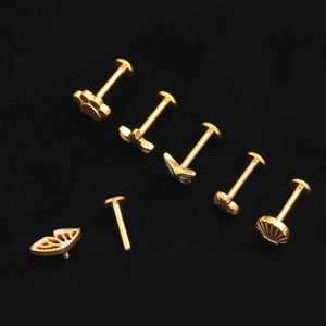 Detailed macro view of G23 titanium gold piercing studs with butterfly and star shapes