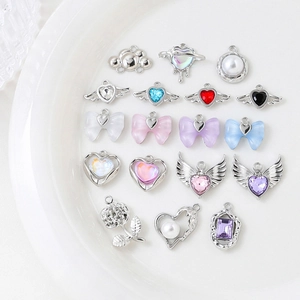 Assorted DIY jewelry charms featuring hearts, bows, and pearls on a white display plate
