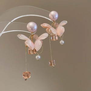 Vista macro di orecchini a nappa con fiori, perle rosa e catene dorate