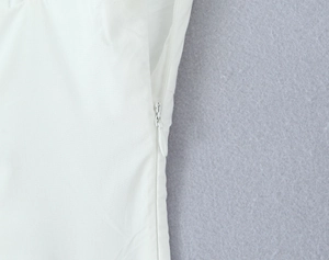 Détail d'une robe blanche montrant une fermeture éclair invisible soignée et la texture du tissu