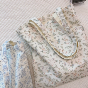 Detail von blauen Cartoon-Stofftaschen mit süßen Hasen- und Enten-Blumenillustrationen